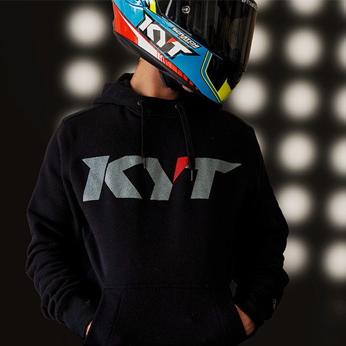 Model facing the camera wearing a KYT branded black long sleeve hoodie.
