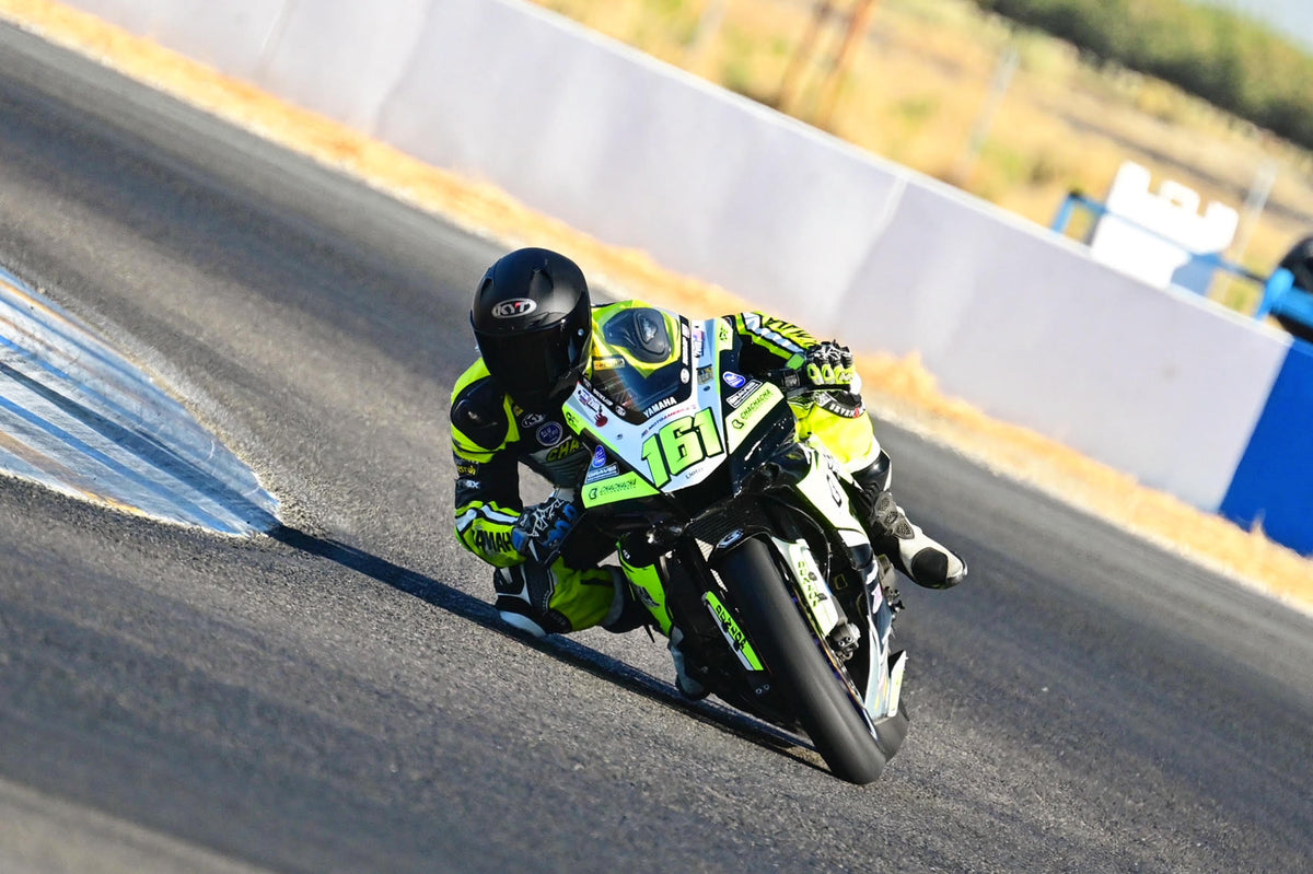 Sal Zvik attacking a corner, dragging his knee, on his Yamaha R6. Yellow and black leathers with a matte black KYT NZ-Race Motorcycle Helmet
