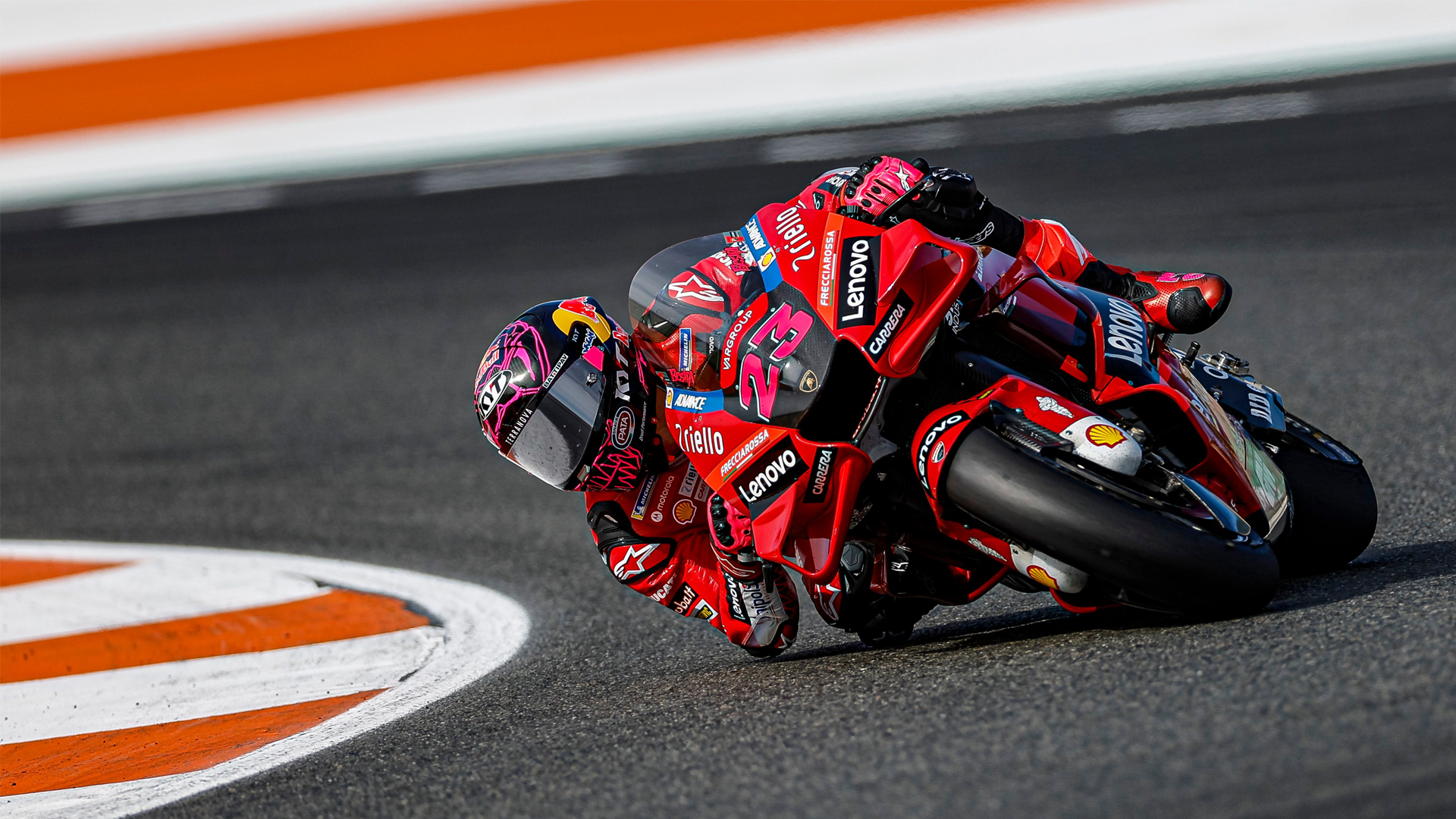 KYT rider Enea Bastianini on his red Ducati in MotoGP dragging knee, wearing a pink and black KX-1 Race GP