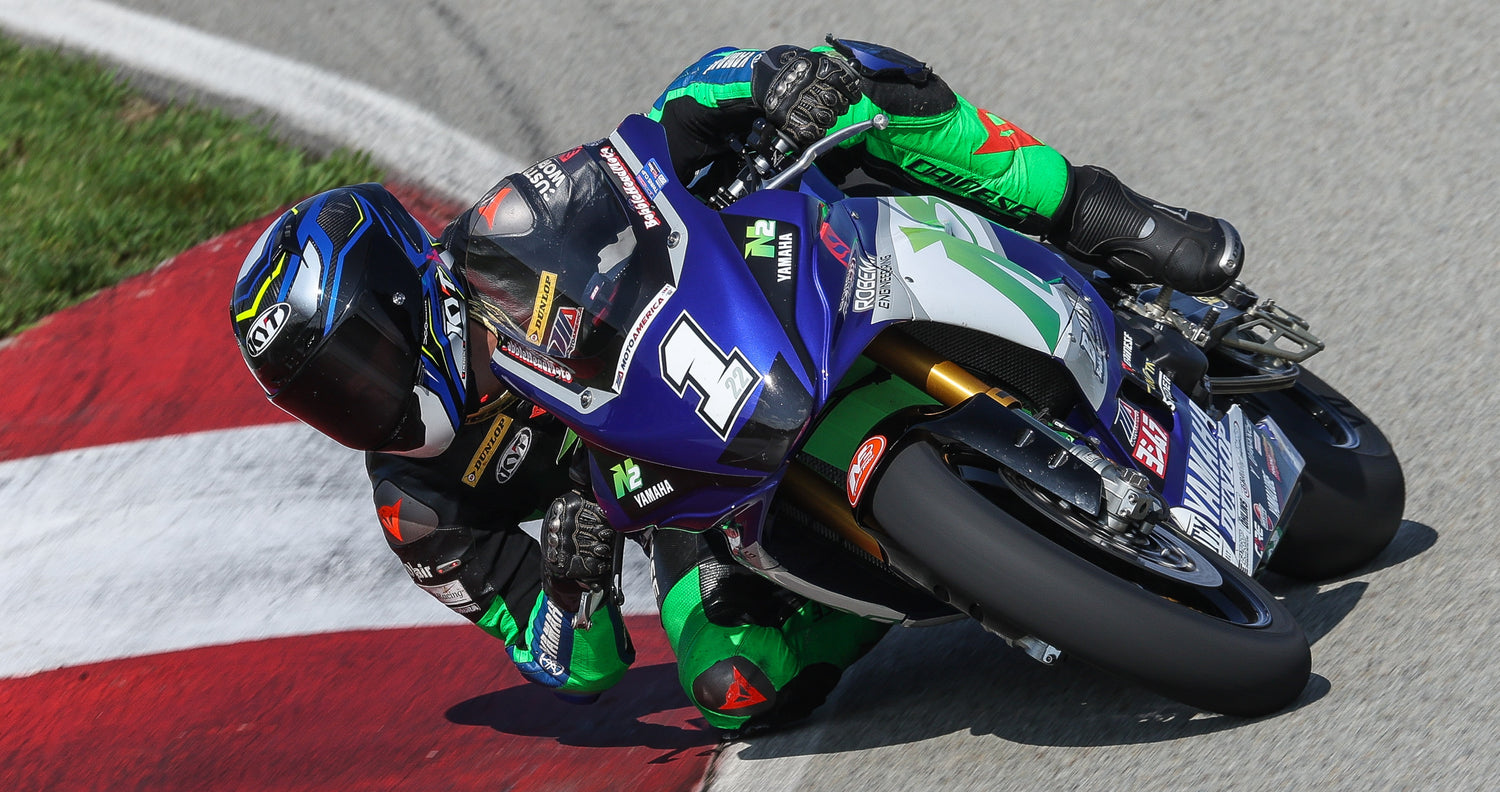 KYT rider Blake Davis riding his N2 Trackdays blue and white Yamaha, dragging knee, in his blue carbon NZ-Race helmet