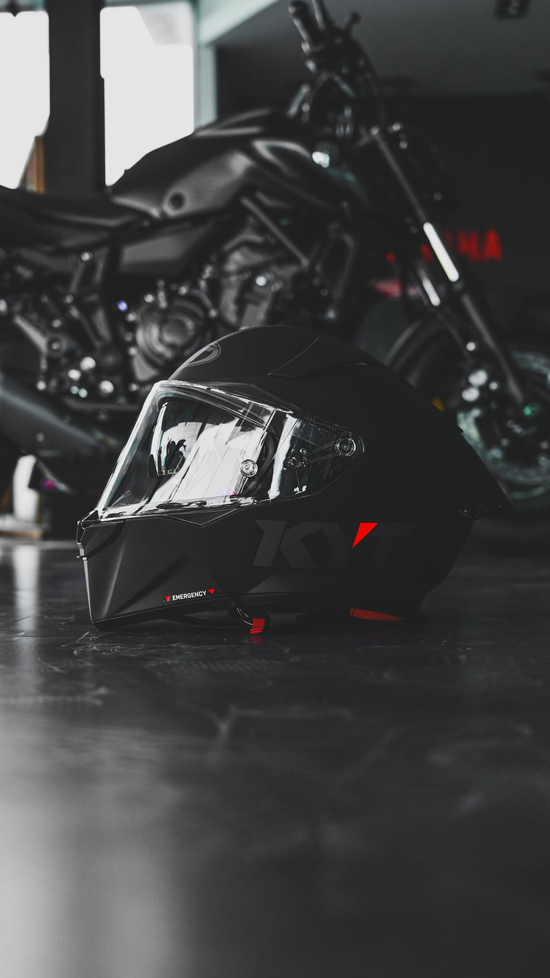 KYT R2R in all black in the floor of a garage in front of a motorcycle