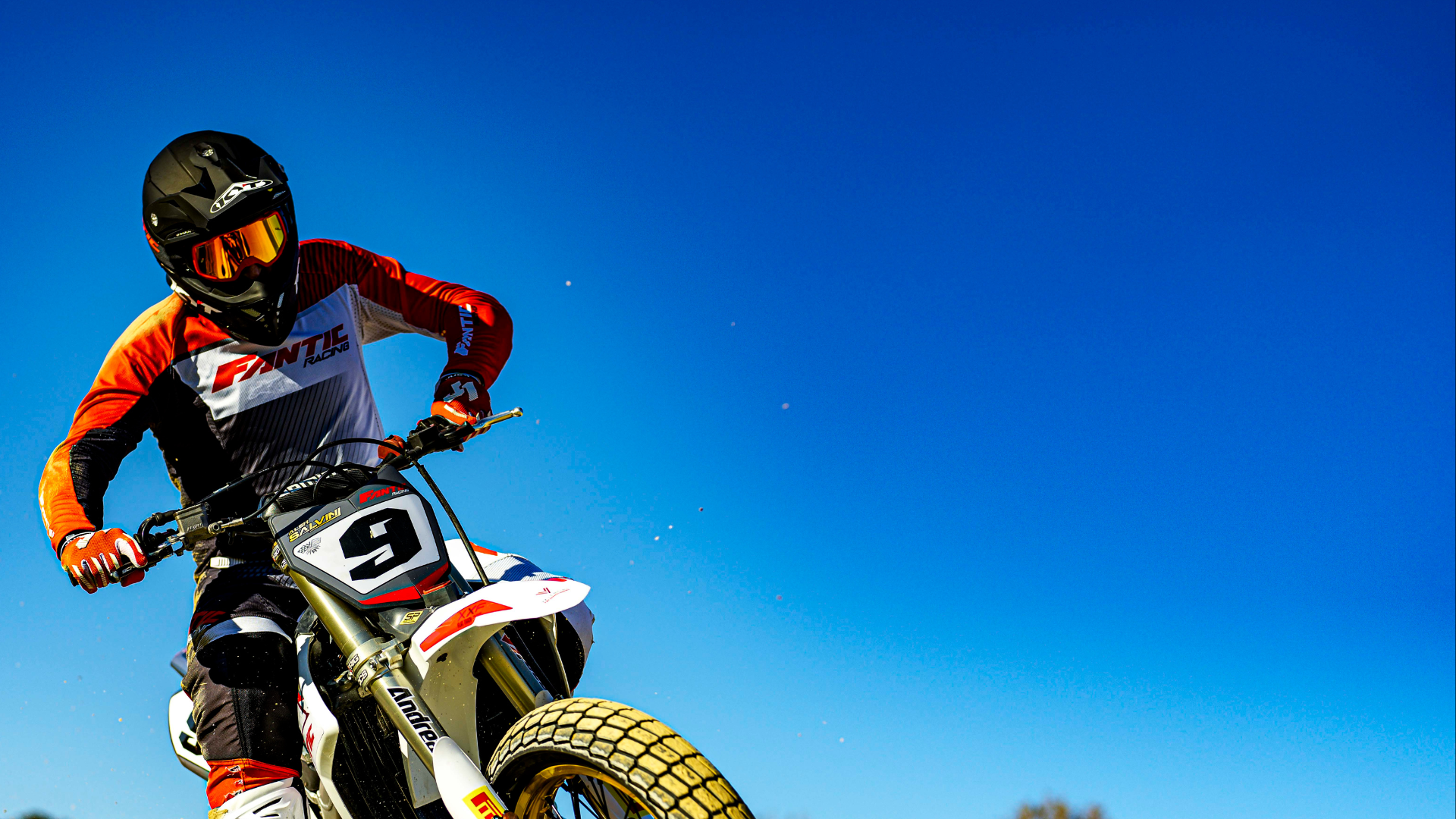 KYT rider, Alex Salvini of Fantic Racing in the air after a jump in a black KYT Skyhawk motocross helmet.